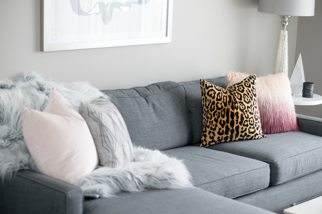 neutral living room, winter home decor, faux fur throw on couch, blush leopard throw pillow, gray couch